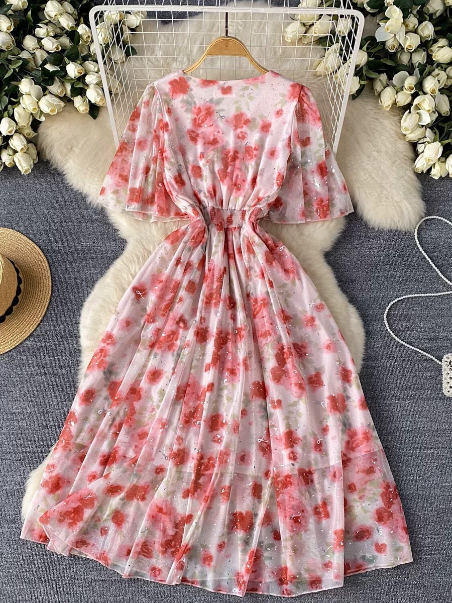 Flat lay of the Rosalie Bloom Organza Midi Dress showcasing the pink floral organza fabric, V-neckline, flutter sleeves, and elegant flowing skirt.