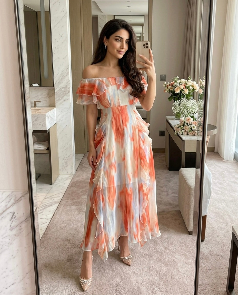 Woman wearing Coral Mist off-shoulder ruffle maxi dress taking a mirror selfie inside a luxury hotel suite with elegant vacation styling.