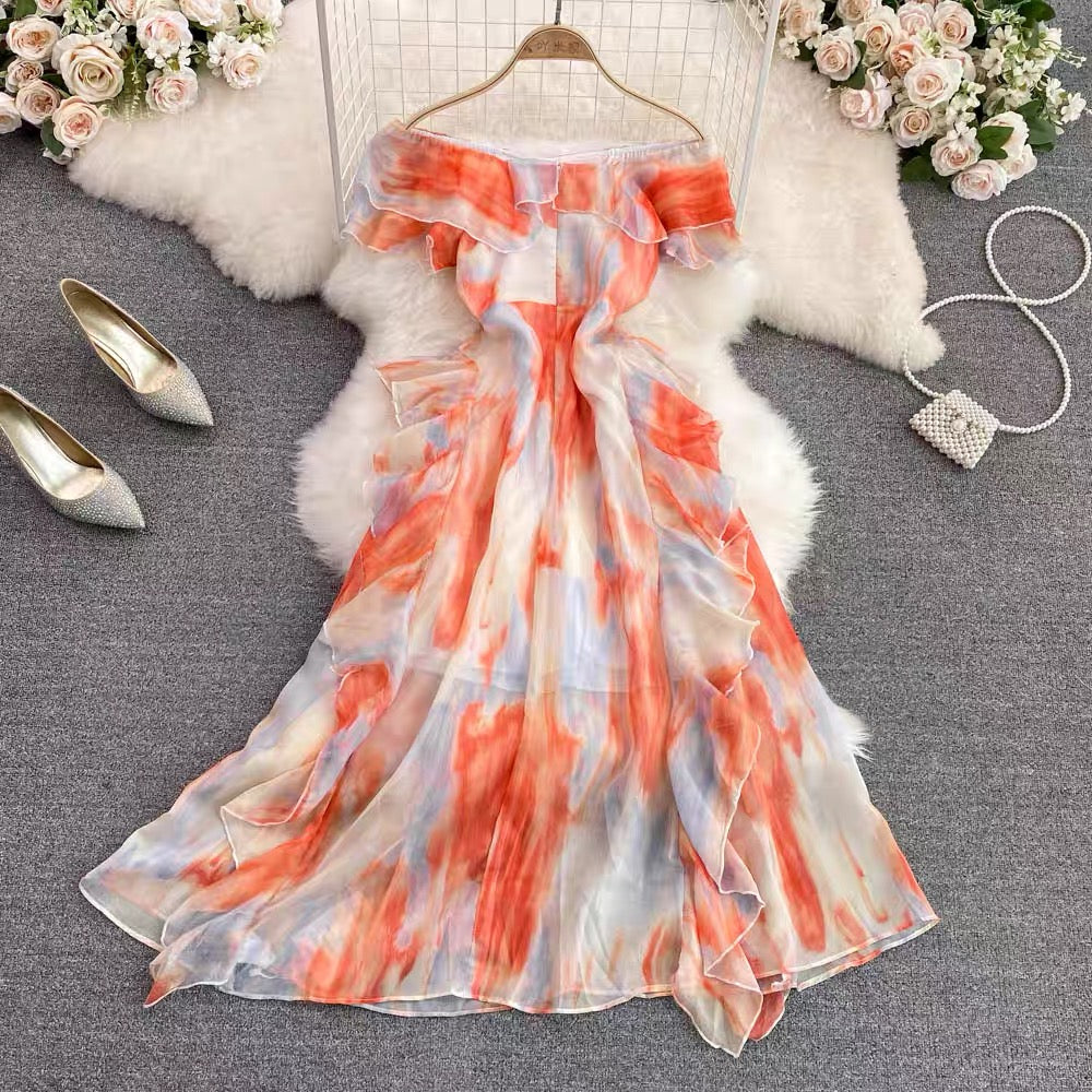 Coral Mist off-shoulder ruffle maxi dress in coral peach watercolor print featuring a flowing resort wear silhouette for vacations, brunches, and summer occasions.